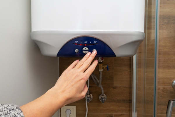 Cropped view of a woman's hand turning on and adjusting water heater temperature