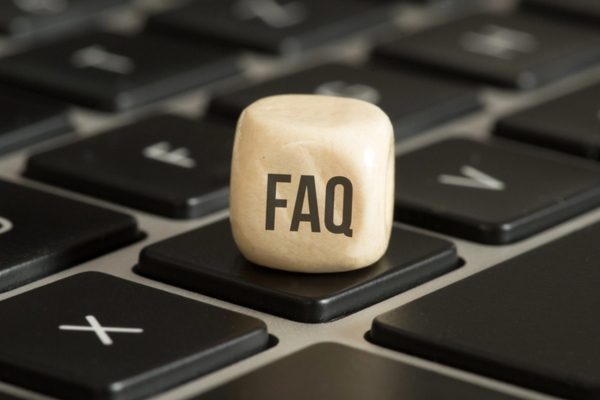 FAQ written on a small wooden cube placed on top of a keyboard depicting questions about oil delivery company