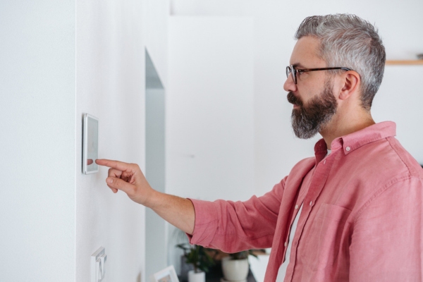 man adjusting home's thermostat