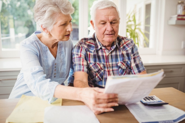 senior couple looking at and discussing energy bill depicting ways to reduce heating bills