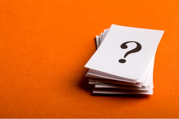 question mark on a stack of paper with orange background depicting FAQs about propane companies