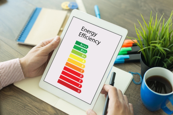 cropped view of a man's hand holding a smart tablet with energy efficiency meter displayed on screen depicting heating efficiency